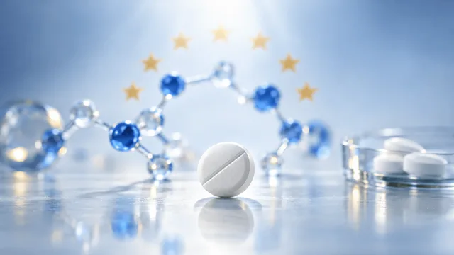 A single white tablet in sharp focus on a glass surface, surrounded by softly blurred abstract molecular shapes and a faint ring of pale gold stars in the background, evoking a new oral medication nearing European regulatory approval.