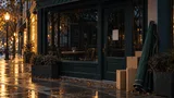 A darkened, closed coffeehouse storefront at dusk with empty chairs inside and moving boxes stacked near the entrance, surrounded by lit neighboring shops.